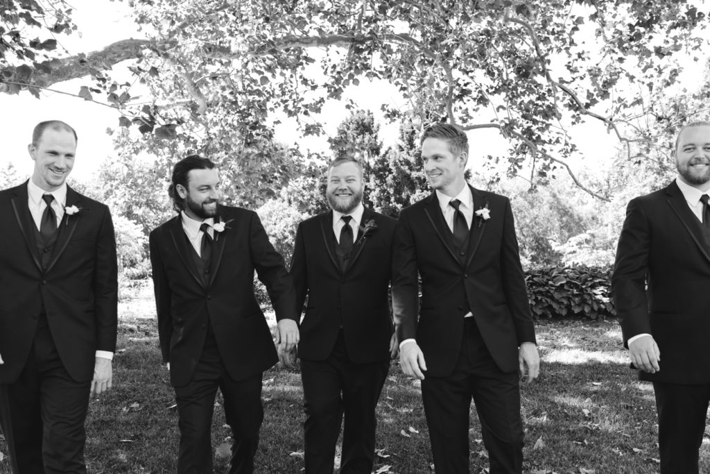 groom and groomsmen walking and smiling in black an white