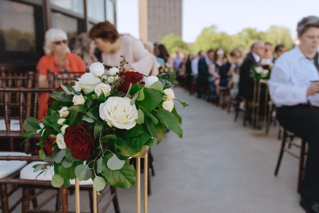 white and red roses with greenery on gold stand lining the outdoor aisle