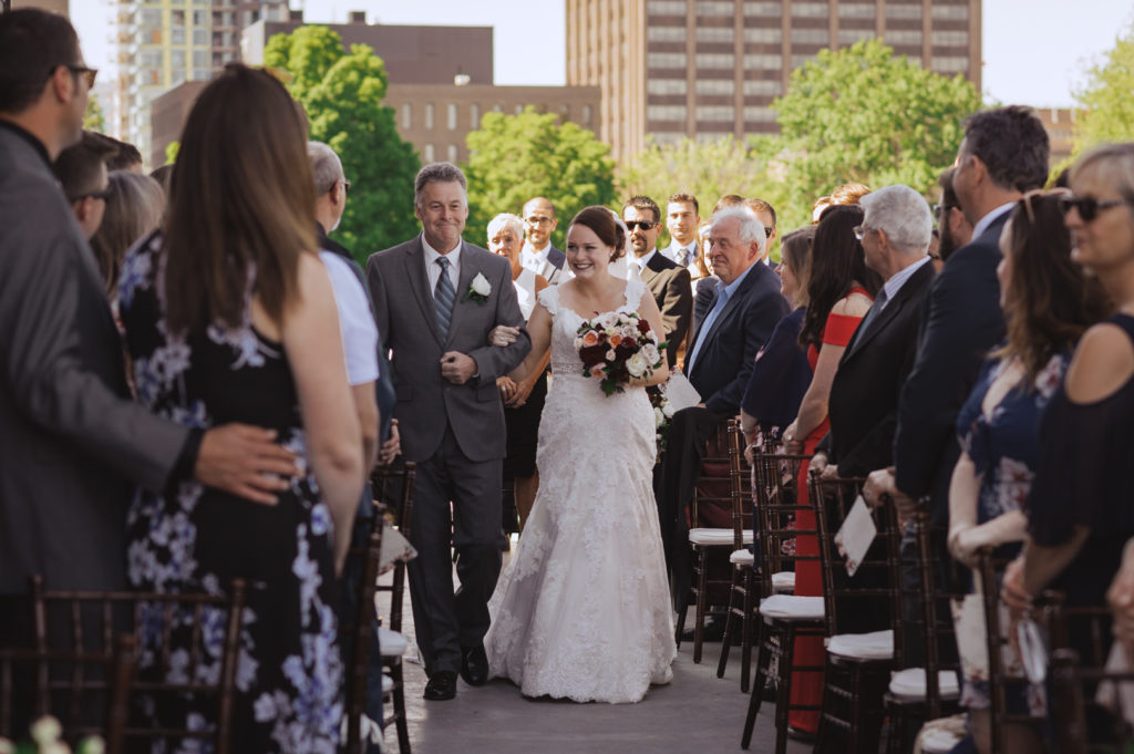 bride walking down the aisle with her father smiling at guests