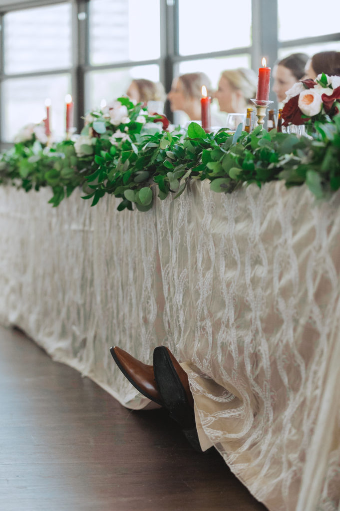 groomsman's feet crossed peeking out from underneath the table cloth