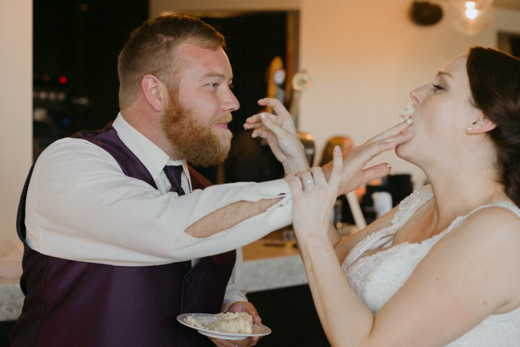 Groom smushing cake into the bride's mouth