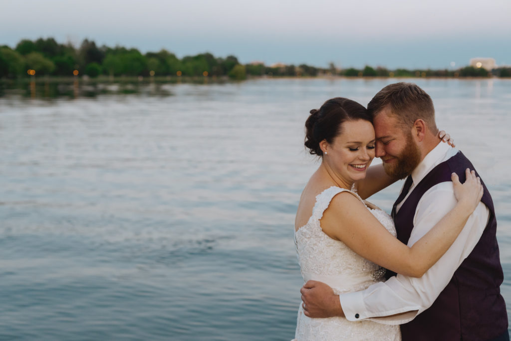 bride and groom cuddling at sunset by dows lake
