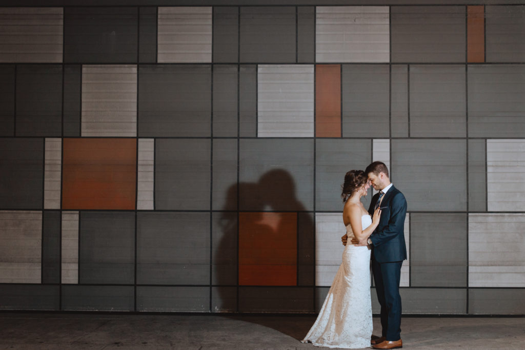 bride and groom in front of checkered wall at Landsdown Park