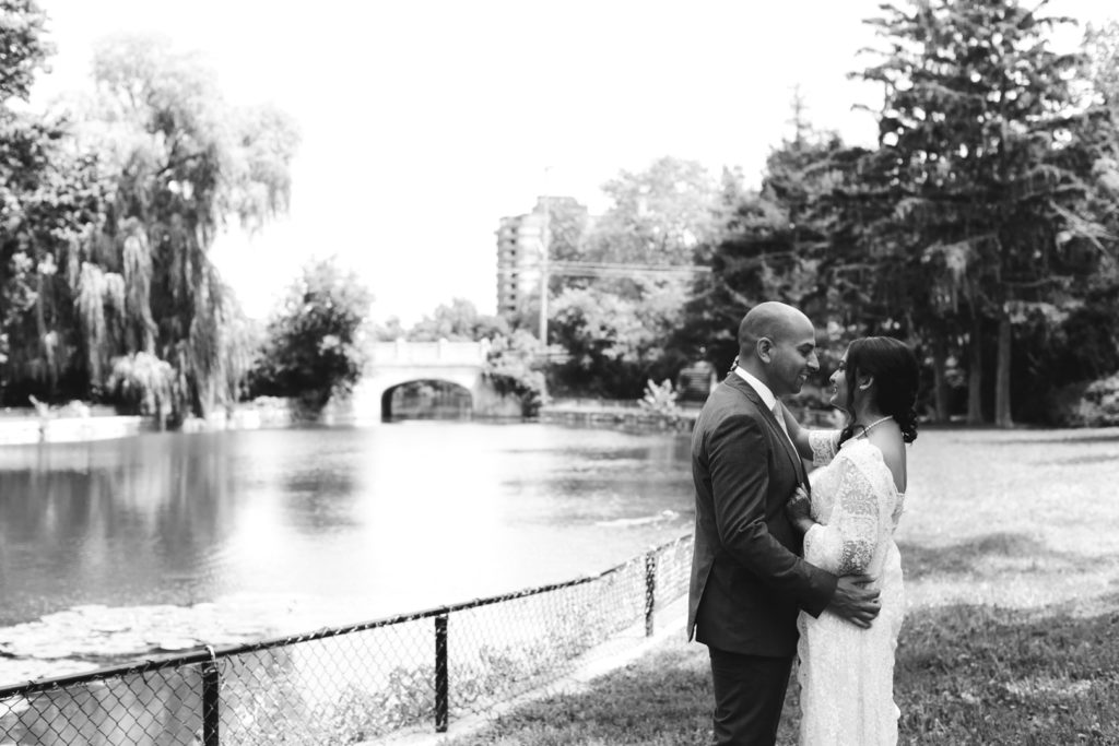 bride and groom cuddling by the pond
