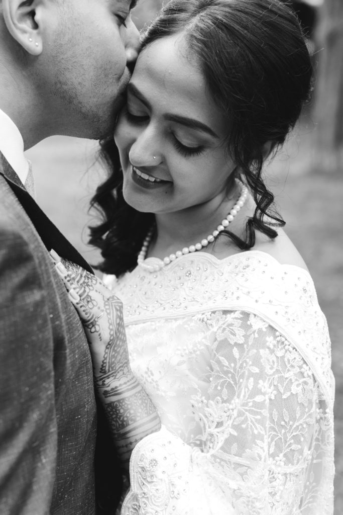 groom kissing the bride in black and white