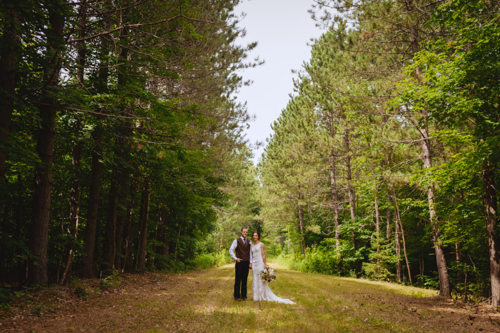 bride and groom holding hands in a tree lined path