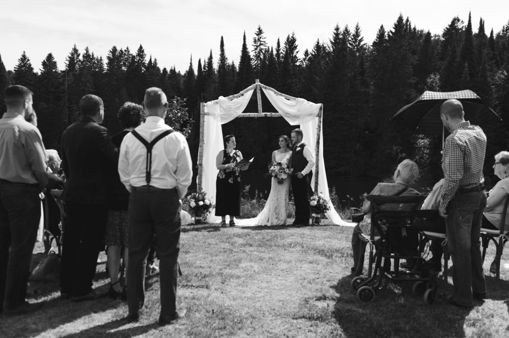 black and white photo of wedding ceremony at family cottage under a birch tree altar