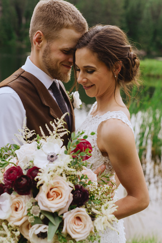 bride and groom cuddling close with wild floral bouquet