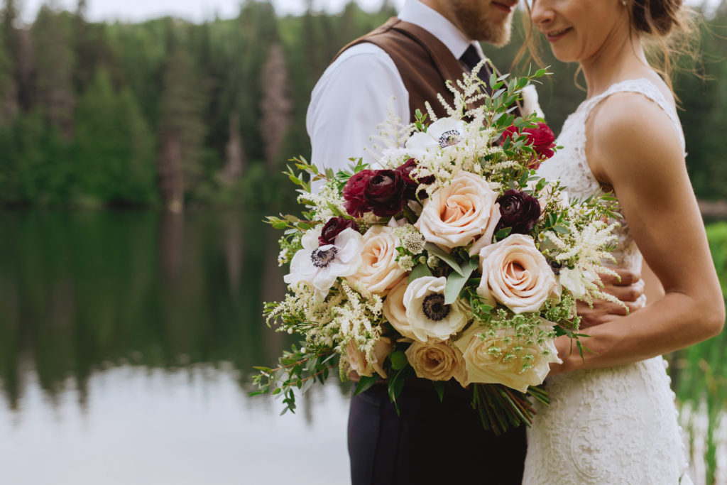 bride and groom cuddling with big floral bouquet