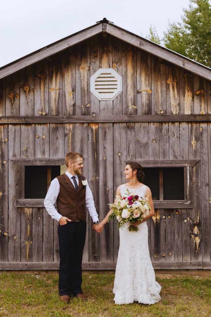 bride and groom holding hands in front of chicken coop