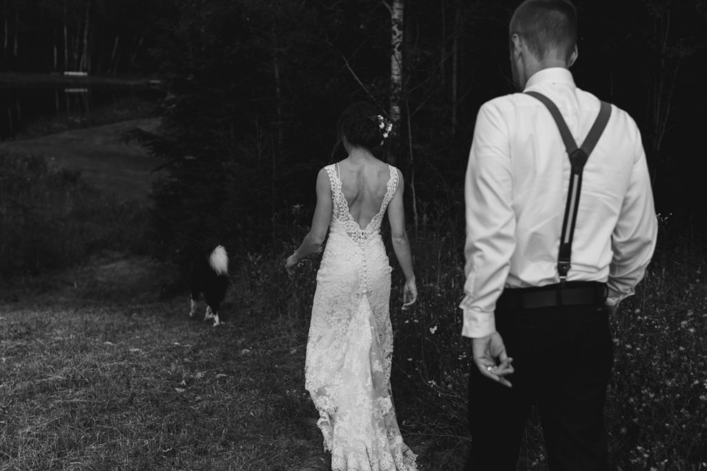 bride and groom walking down a hill with their dog