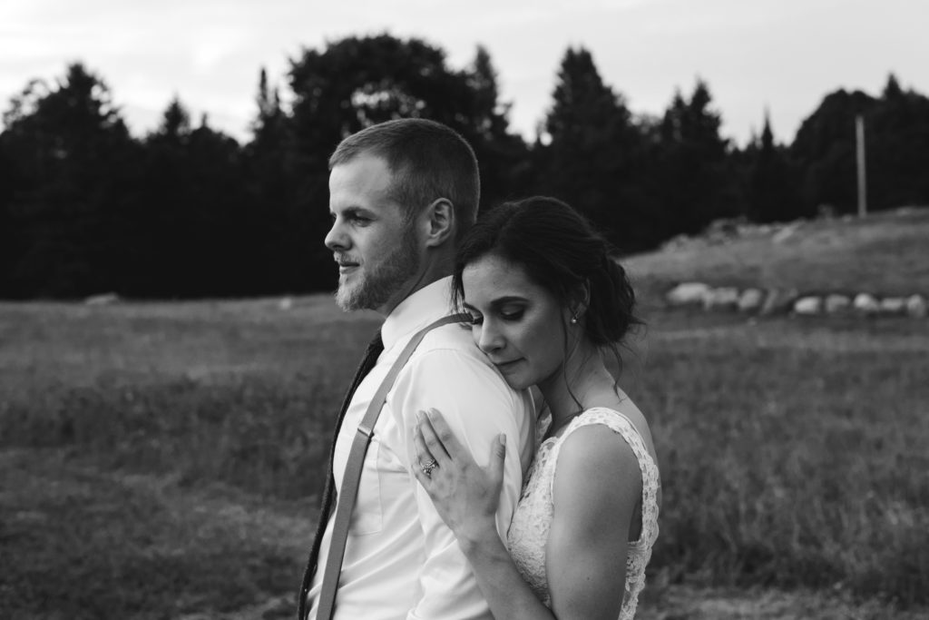 black and white photo of bride cuddling up to groom