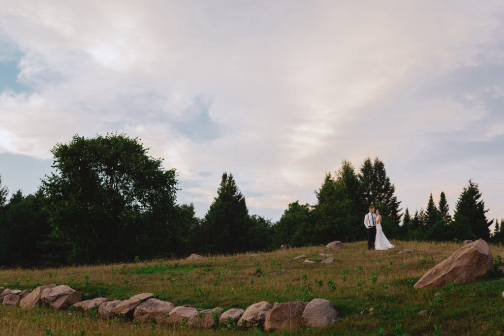 photo of bride and groom in a goat pasture at sunset