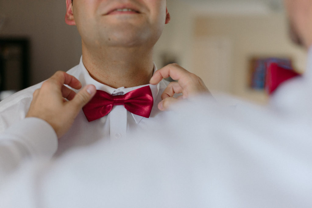 adjusting groomsman's red bowtie