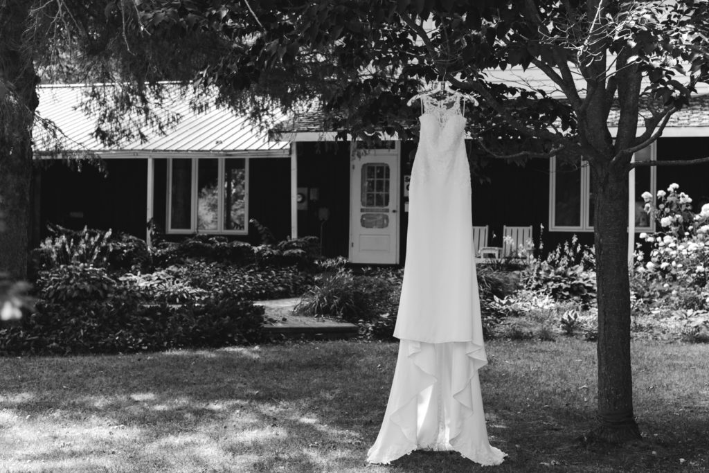 bride's dress hanging from a tree outside farm house in black and white