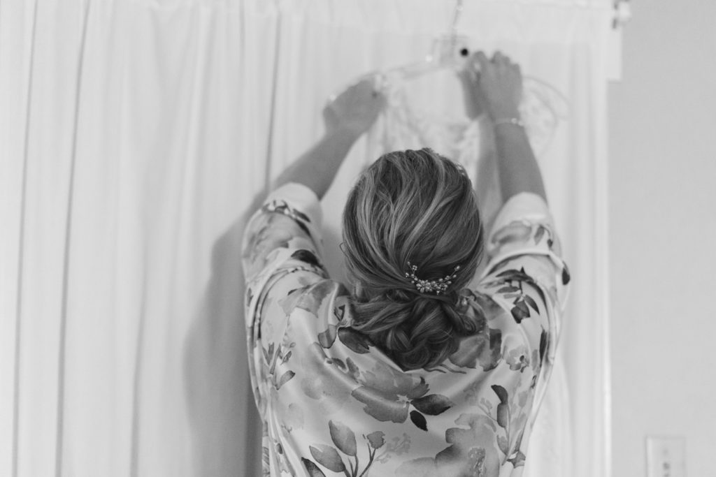 bride reaching for her dress off the hanger