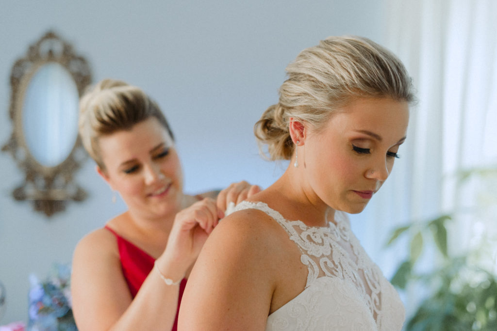 bridesmaids helping the bride into her wedding dress