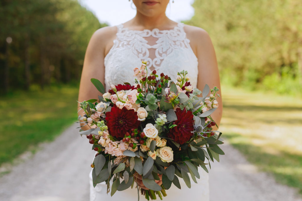 bride standing on dirt road holding bouquet