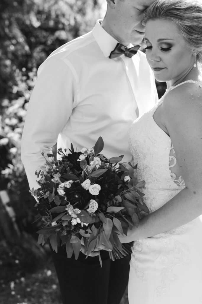 bride and groom cuddling with bouquet black and white