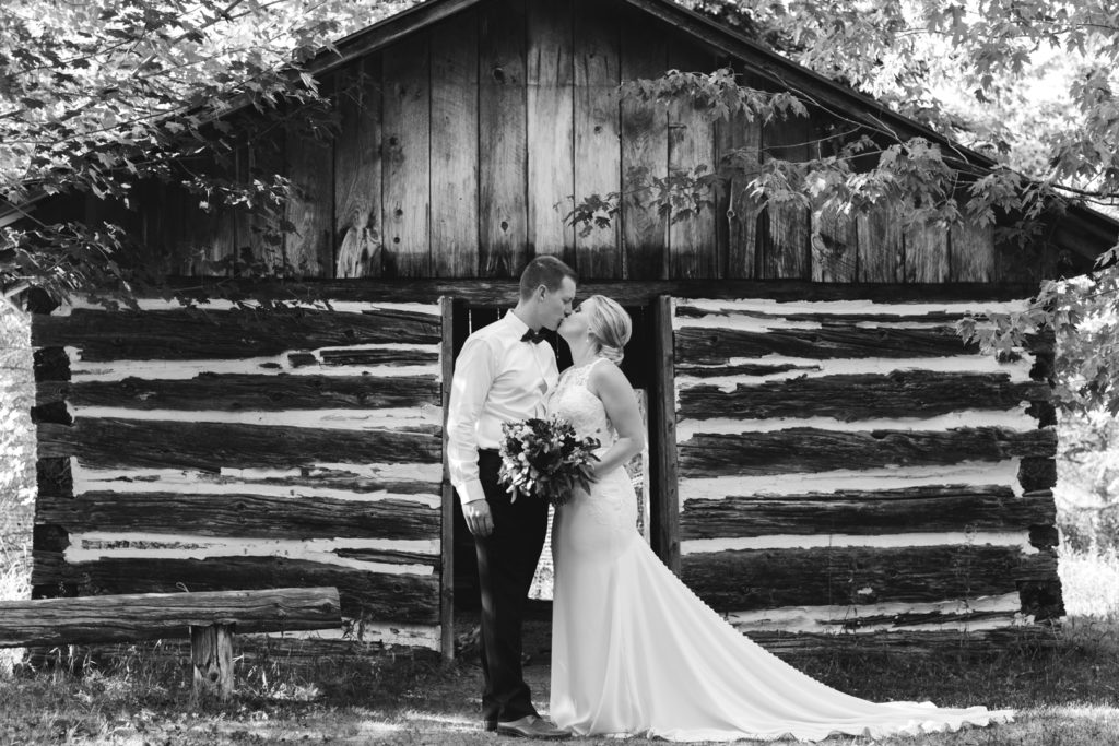 bride and groom kissing in front of wooden shed