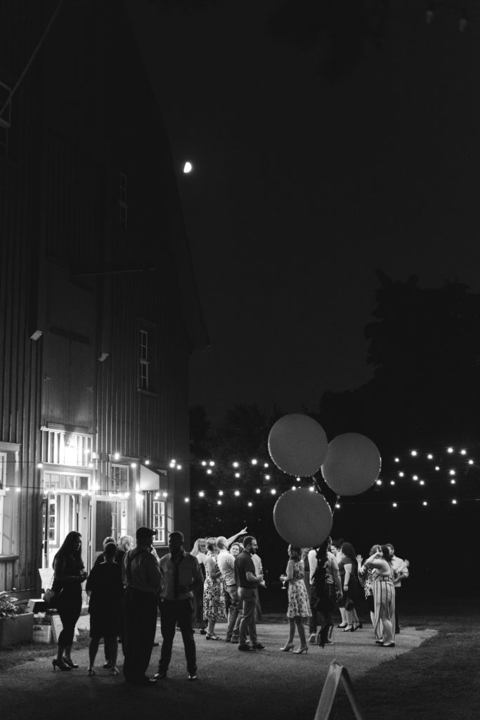 wedding guests dancing outside barn with twinkly lights