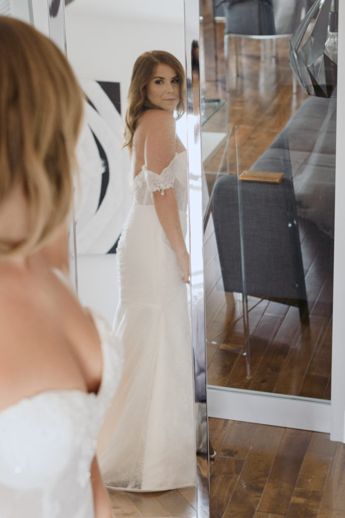 bride looking at herself in the mirror after getting dressed