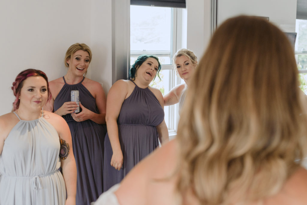 bridesmaids seeing the bride for the first time in her wedding dress