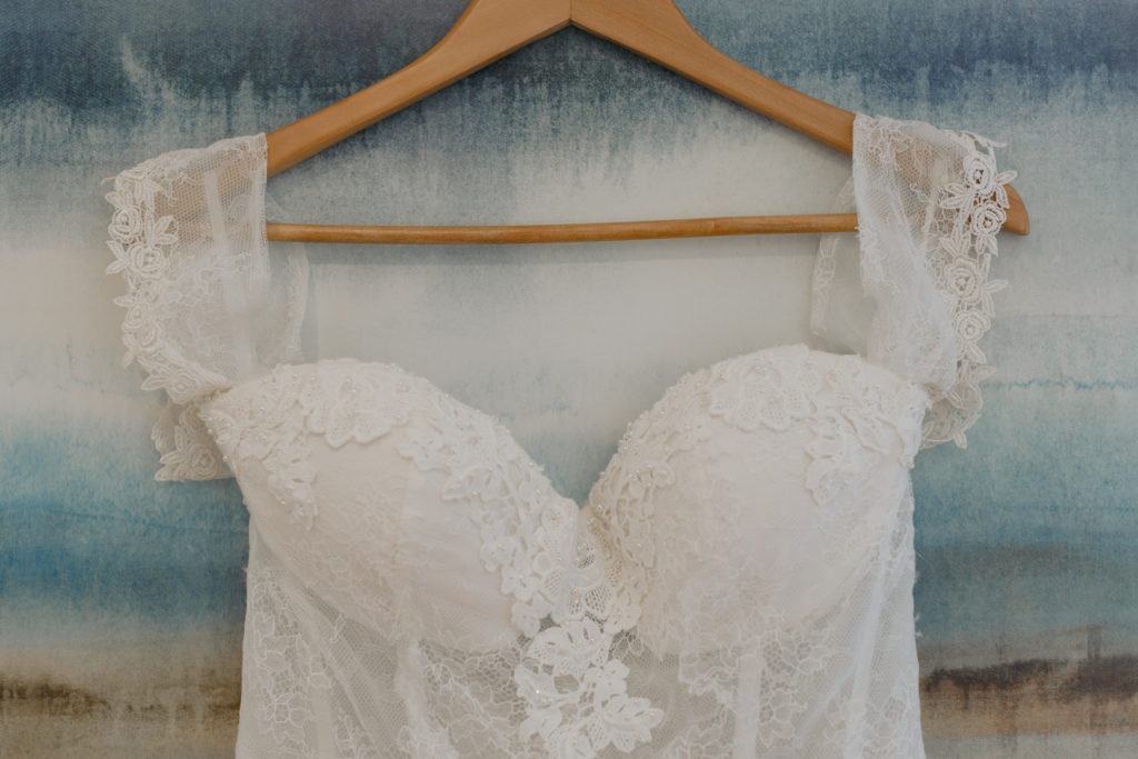 wedding dress hanging in front of blue painting