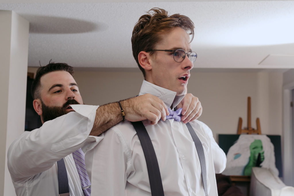 groom adjusting the groomsman's bowtie