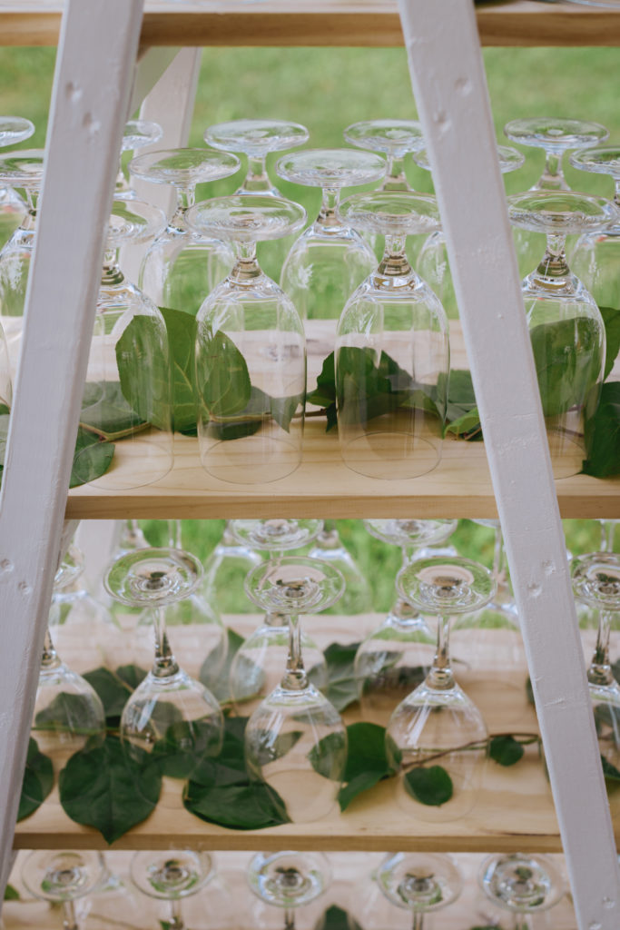 wine glasses set up with greenery around them for outdoor cocktail hour