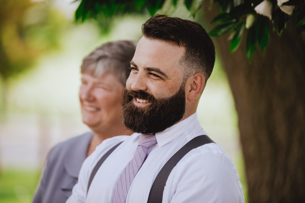 groom smiling as his bride walks down the aisle