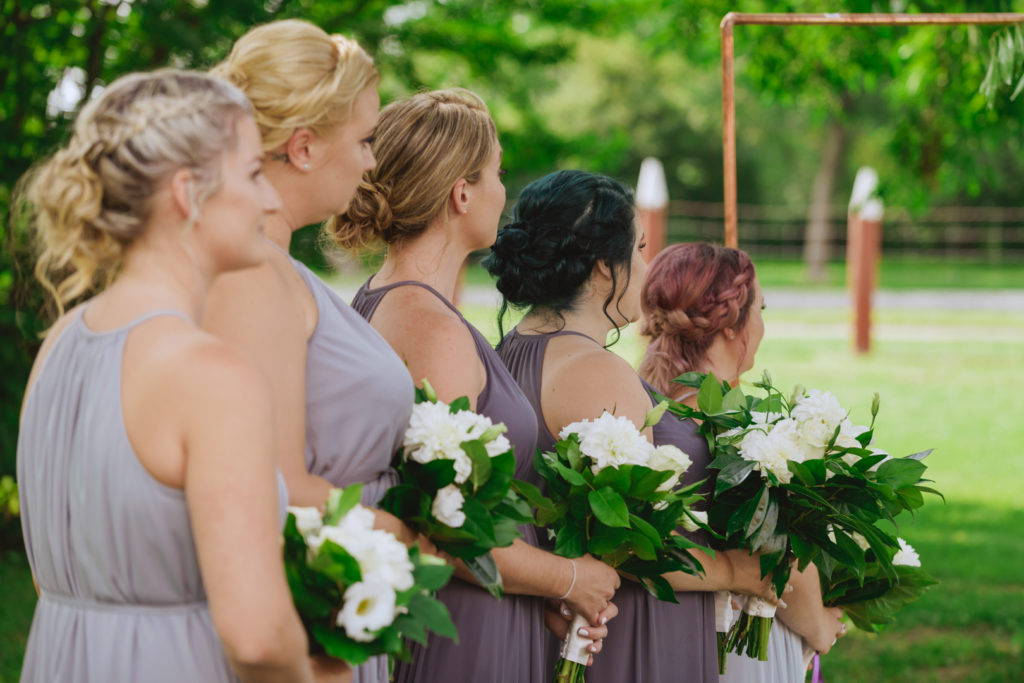 bridesmaids holding bouquets during outdoor wedding ceremony