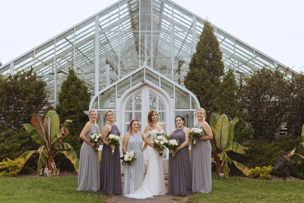 bridesmaids standing in front of the greenhouse at the experimental farm