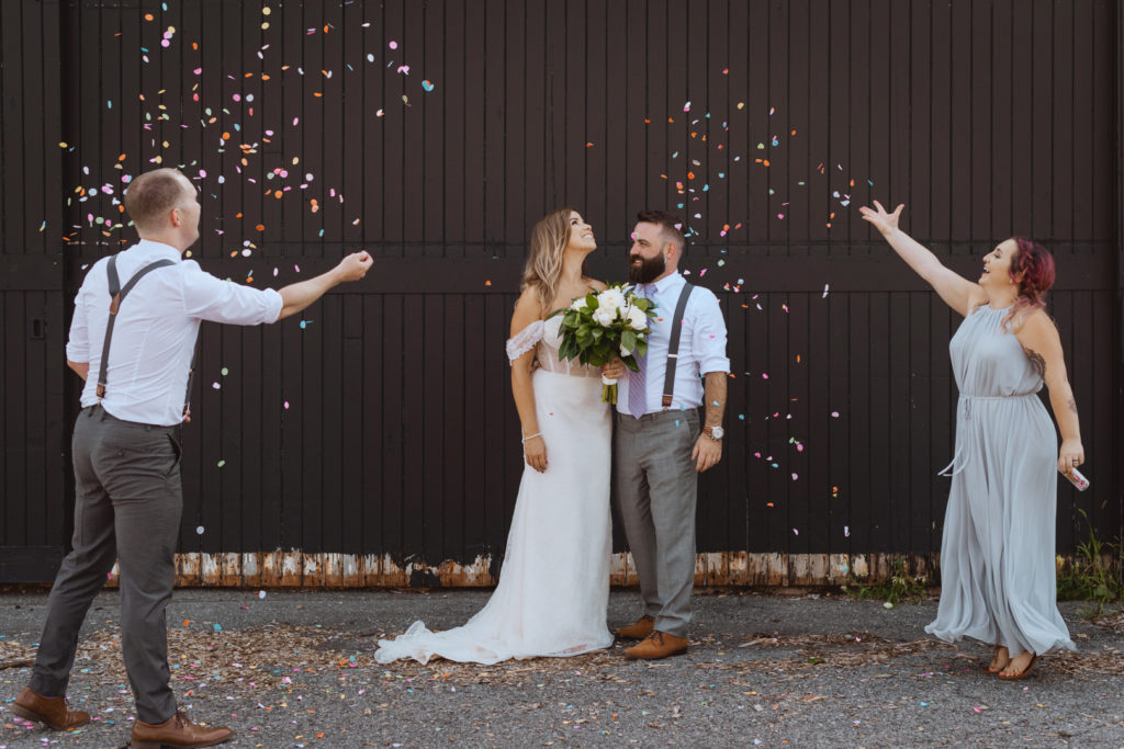 maid of honour and best man throwing confetti on bride and groom