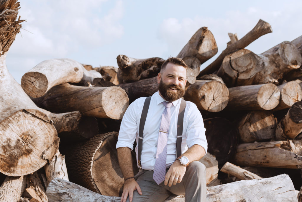 groom sitting on a pile of logs