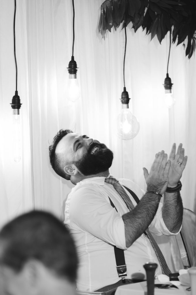 groom laughing at speech during wedding reception