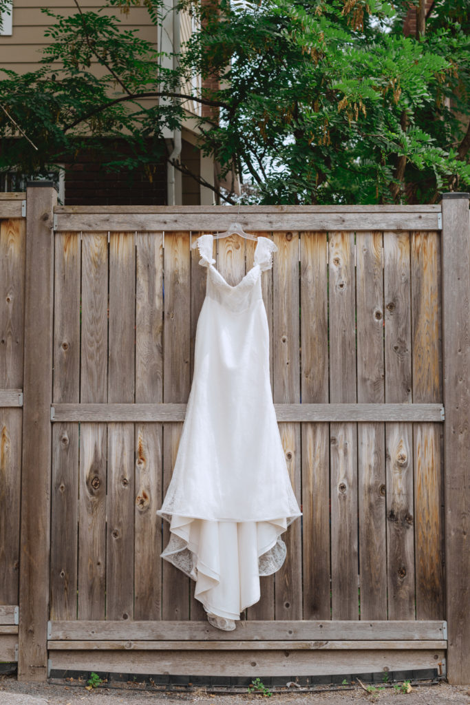 wedding dress hanging from wooden fence