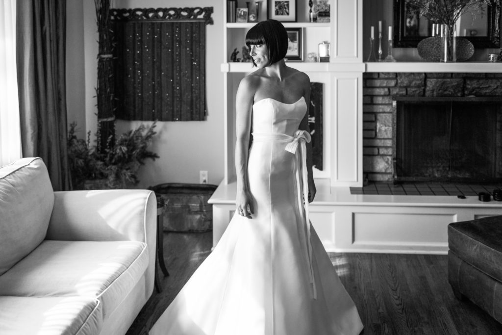 bride wearing wedding dress standing by the living room window