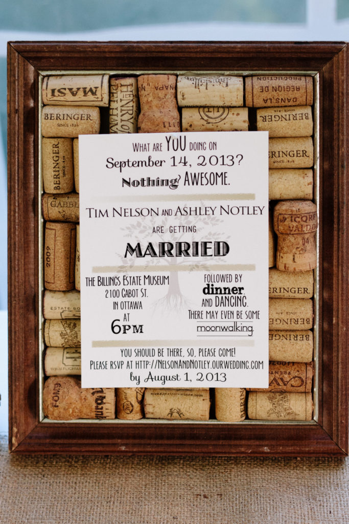 wedding invitation on a wine cork board