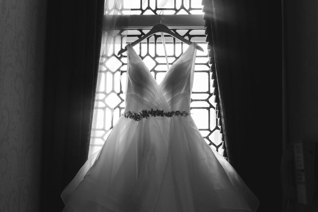 wedding dress hanging in front of vintage window