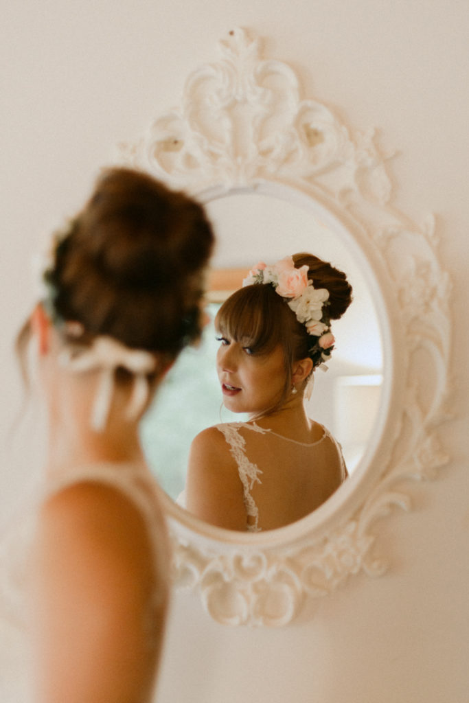 bride looking at the back of her dress in the mirror