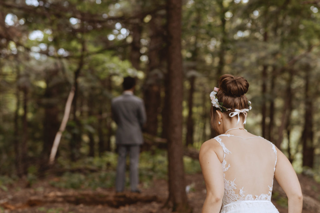 bride walking into the forest where groom is waiting to see her for the first time