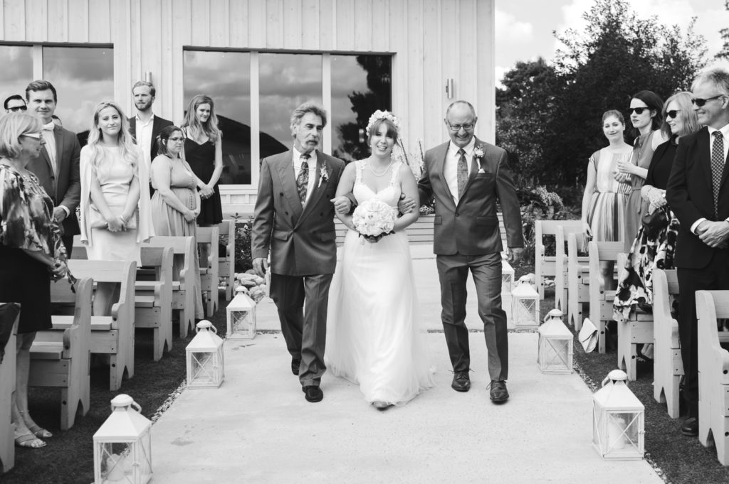 bride and her two fathers walking her down the aisle