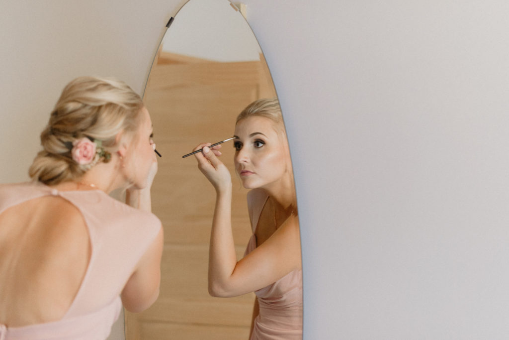 bridesmaid doing her makeup in the mirror