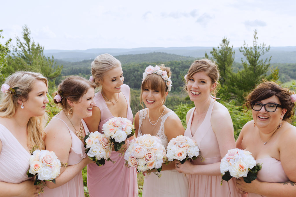 bride and bridesmaids laughing on cliffside