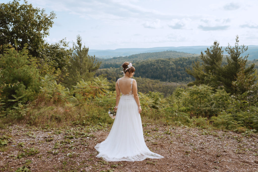 bride standing on a cliffside overlooking Gatineau Hills