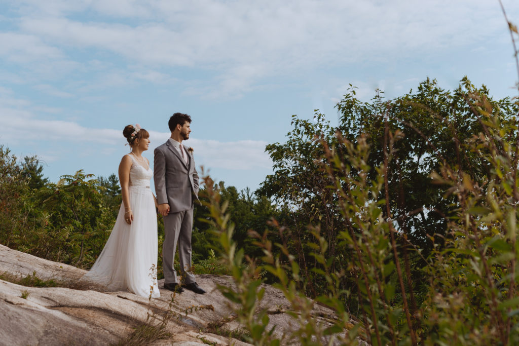 bride and groom standing on a cliff overlooking the Gatineau Hills