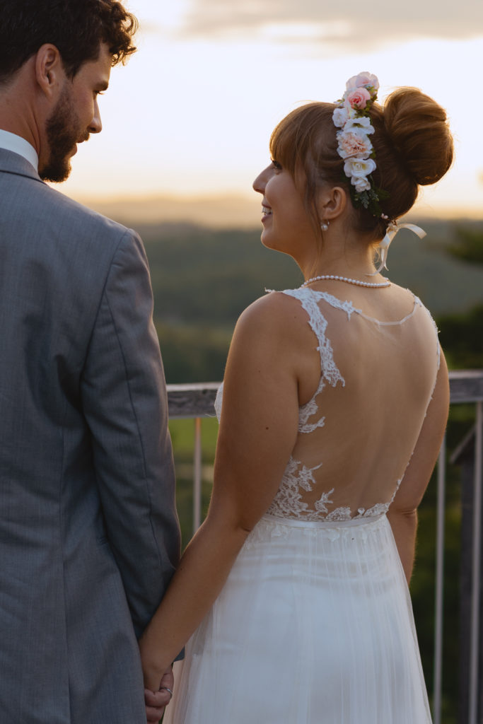 bride and groom smiling at each other at sunset on a cliff