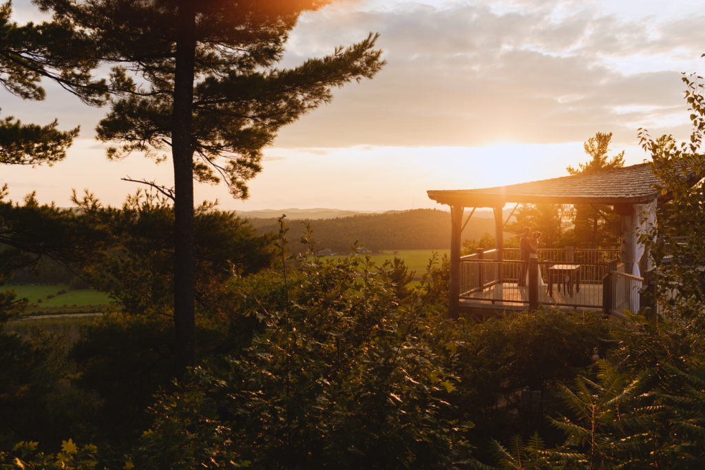 bride and groom standing under gazebo at sunset on a cliff