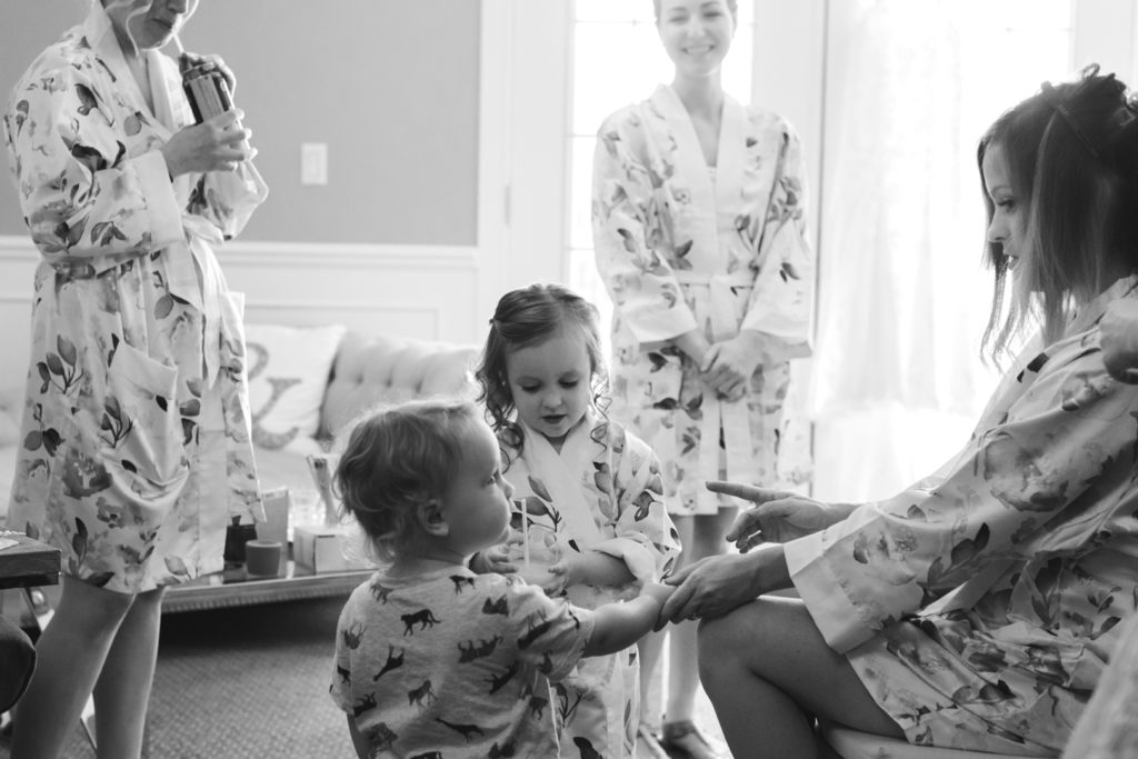 bridesmaid having her hair done with the flower girl and ring bearer holding her hand